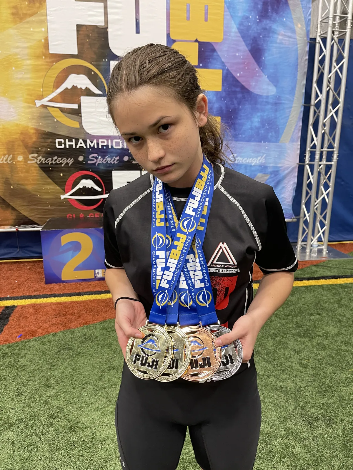 A young 317 Jiu-Jitsu student holding the medals won at a tournament