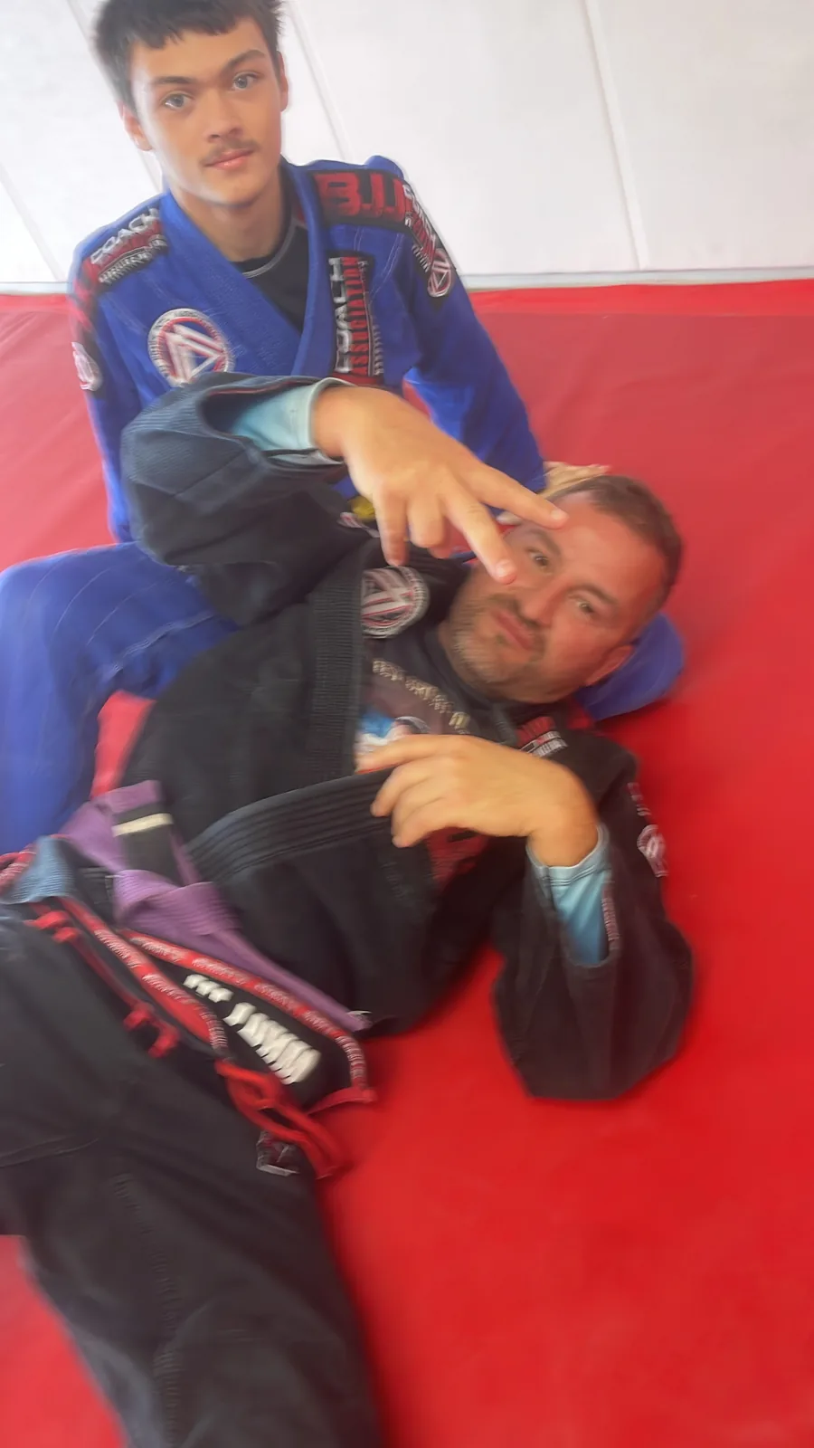 Adults rolling on the academy mats